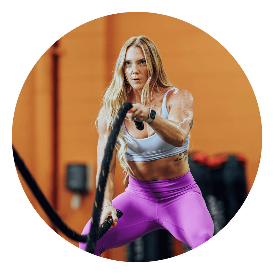 Fit woman using battle ropes in the gym.